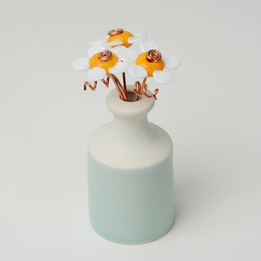 Miniature pale teal porcelain bottle vase with yellow and white glass daisies