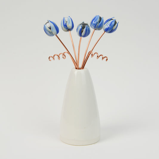 Miniature white porcelain cone vase with streaked blue glass tulips