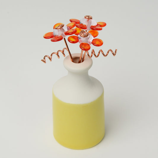 Miniature yellow porcelain bottle vase with orange glass daisies